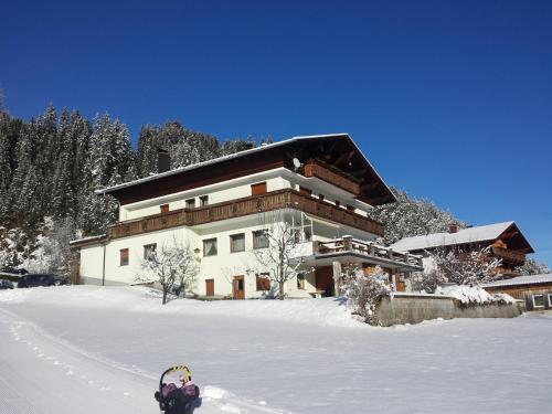 a building in the snow with a child in front of it at Gästehaus Hauser in Bach