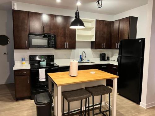 eine Küche mit einem schwarzen Kühlschrank und einem Holztisch in der Unterkunft Private Bedroom Fountain Square - Shared in Indianapolis