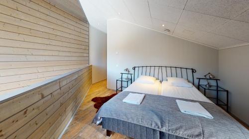 a bedroom with a bed and a wooden wall at Sandy Kelt - Irish House Apartments in Kalajoki