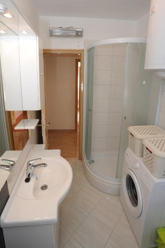 a bathroom with a sink and a washing machine at Voshta 2 bedroom apartment in Zadar