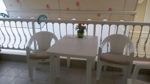 a white table with two chairs and a vase with flowers at Seaflows Apartments #3 in Paralia Katerinis