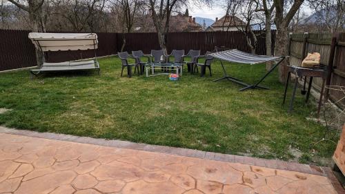 a yard with chairs and a table and a fence at Casa Beatrice in Călimăneşti