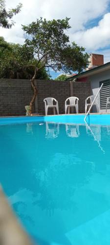 una piscina azul con 2 sillas y un árbol en Sara Home en Garupá