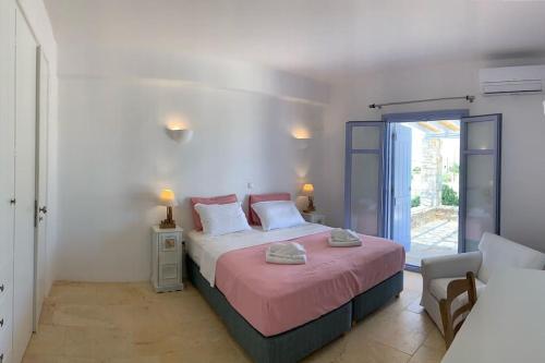 a bedroom with a large bed with a pink blanket at Villa Laugh, on The Limnes Beach in Kampos Paros