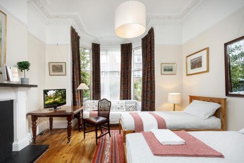 sypialnia z 2 łóżkami, biurkiem i telewizorem w obiekcie Sheen's House w Edynburgu