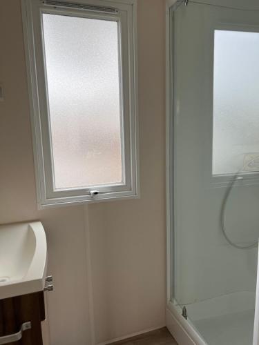 La salle de bains est pourvue d'une fenêtre, d'un lavabo et d'une douche. dans l'établissement Mobilhome 5 VO32, à Vias