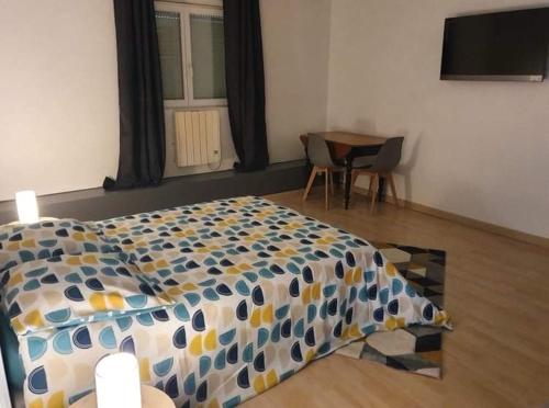 Un dormitorio con una cama, una mesa y un televisor. en Spa du petit manoir, en Hébuterne