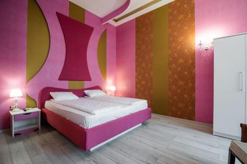 a bedroom with a pink and yellow wall at Apartament La Teatru Boudoir in Oradea