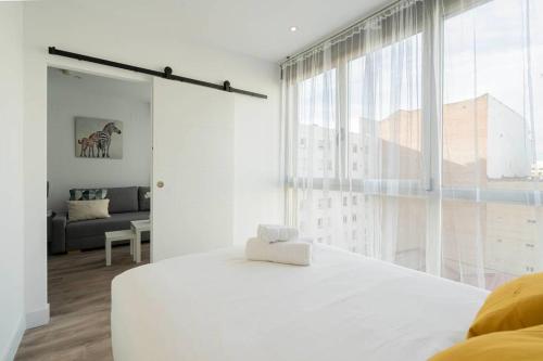 a white bedroom with a bed and a large window at Precioso apartamento en el Barrio Salamanca P A D in Madrid