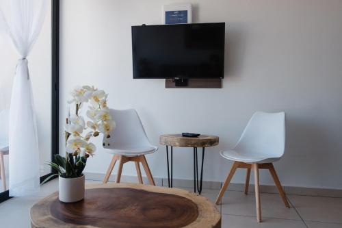 a living room with two white chairs and a table at Departamento Vista Nova Culiacán in Casas