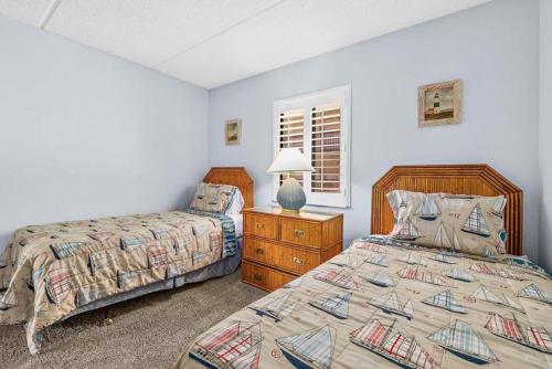 a bedroom with two beds and a table with a lamp at 6206 Courtyard Villa 2nd Fl S in Saint Augustine