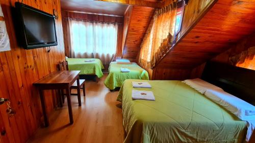 a room with two beds and a table and a tv at Hospedaje, Cabañas y Sauna Tunki Lodge in Oxapampa