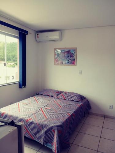 a bedroom with a bed in a room with a window at POUSADA ALVE VERDe in Capitólio