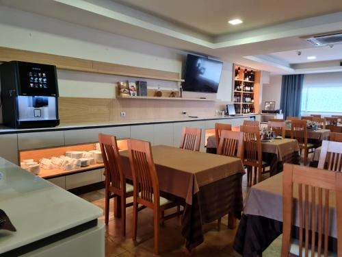 een restaurant met tafels en stoelen en een televisie bij Hotel Albergaria Borges in Chaves