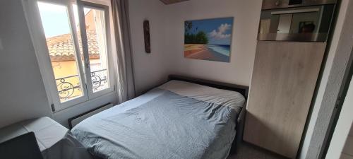 ein kleines Schlafzimmer mit einem Bett und einem Fenster in der Unterkunft Rue du Vieux Chateau - Beau F2 in Menton