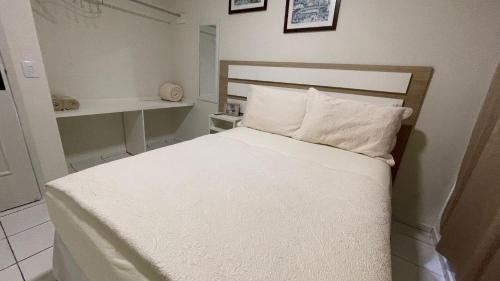 - un lit avec des draps et des oreillers blancs dans l'établissement Apartamento no Centro de Foz do Iguacu, à Foz do Iguaçu