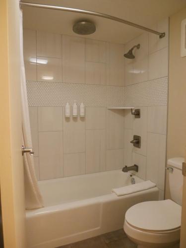 a bathroom with a white tub and a toilet at Days Inn by Wyndham Prescott in Prescott