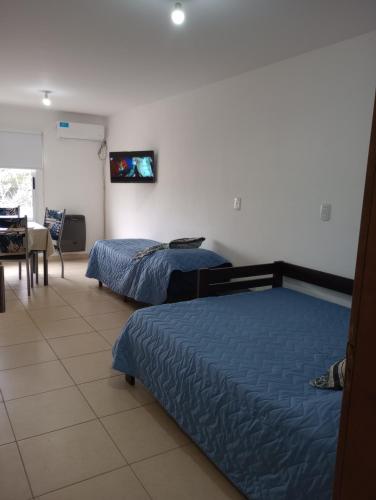 a bedroom with two beds and a table and a television at El Depto de Roberto in Villa María