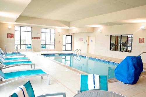 a large swimming pool with blue chairs and tables at TownePlace Suites by Marriott Ames in Ames