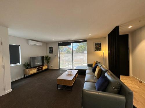 a living room with a couch and a tv at Gem in Papanui Christchurch in Christchurch