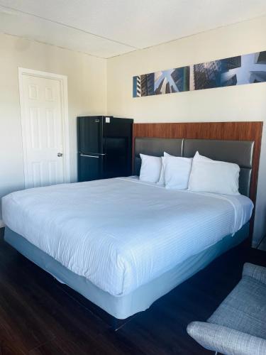 1 cama grande con sábanas blancas y nevera negra en Mystic Sea en Myrtle Beach