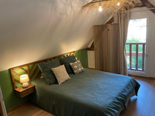 ein Schlafzimmer mit einem grünen Bett und einem Fenster in der Unterkunft Gîte du « Lavoir » à 2 pas de la mer in Saint-Martin-le-Gaillard