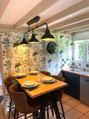 une cuisine avec une table en bois, des assiettes et des verres dans l'établissement Gîte du « Lavoir » à 2 pas de la mer, à Saint-Martin-le-Gaillard