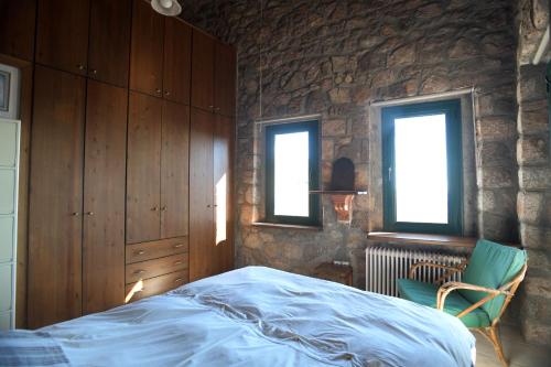 a bedroom with a bed and a stone wall at Stone house with panoramic view in Tiros