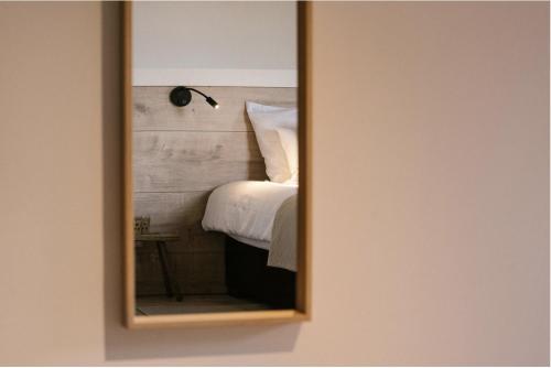 a mirror hanging on a wall next to a bed at Brut the lodges in Reijmerstok