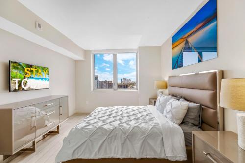 a white bedroom with a bed and a large window at Beachwalk Resort #2301 - MODERN RESORT 3BDR and 3BA - BALCONY, GYM, AMAZING POOL in Hallandale Beach