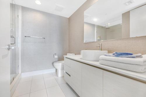 a white bathroom with a sink and a shower at Beachwalk Resort #2301 - MODERN RESORT 3BDR and 3BA - BALCONY, GYM, AMAZING POOL in Hallandale Beach