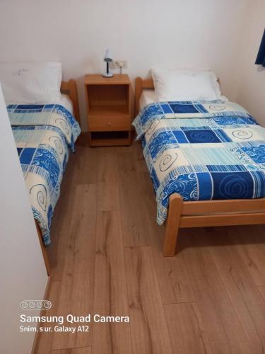a room with two beds and a night stand with a table at Studio 4827-3 for 4 Pers in Nerezine in Nerezine
