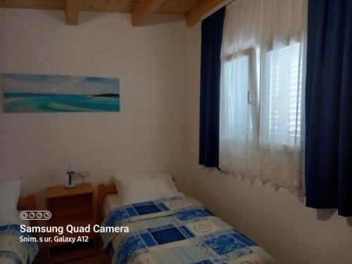 a bedroom with a bed and a window with blue curtains at Studio 4827-3 for 4 Pers in Nerezine in Nerezine