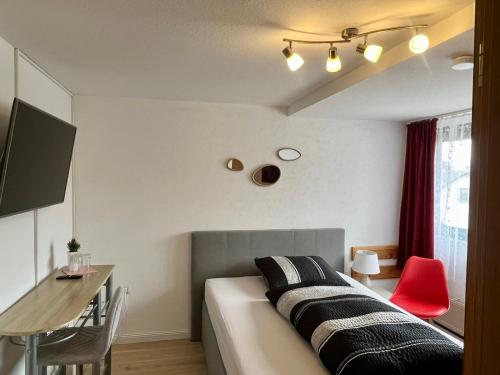 a bedroom with a bed and a desk and a red chair at Gästehaus Ehebachhof Hotel Garni in Müllheim