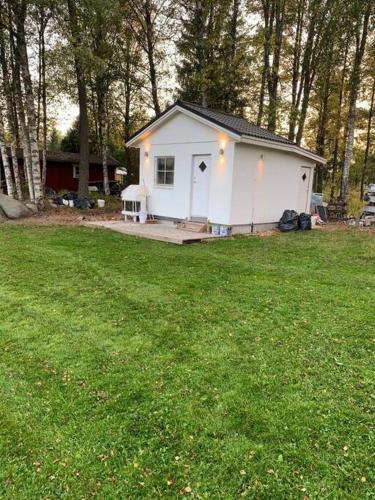 a small white house in the middle of a yard at Trevlig stuga med uteplats in Rimbo