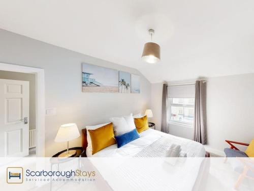 a bedroom with a bed with yellow and blue pillows at Scarborough Stays - Norwood House in Scarborough