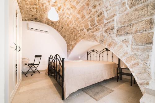 1 dormitorio con cama y pared de ladrillo en Corte Birù, en Bitonto