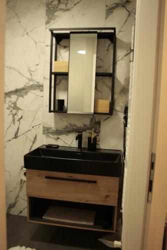 ein Bad mit einem schwarzen Waschbecken und einem Spiegel in der Unterkunft Kaj-Lux in Tuheljske Toplice