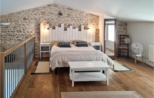 1 dormitorio con 1 cama grande y pared de piedra en 2 Bedroom Lovely Home In Saint-just-luzac, en Saint-Just