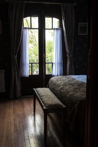 a bedroom with a bed and a bench in front of a window at Hotel City Bell in La Plata