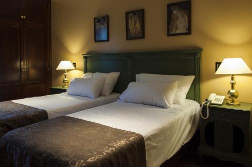 two beds in a room with two lamps and a phone at Hotel City Bell in La Plata