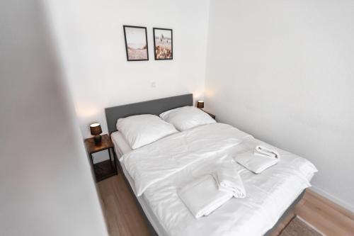 1 cama con sábanas blancas y almohadas en una habitación en Koje Sechs I Apartment im Zentrum mit Hafenblick, en Bremerhaven