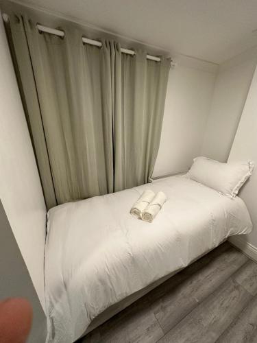 um pequeno quarto com uma cama branca e cortinas em Single Room 9 em Londres