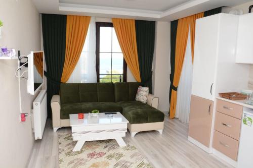 ein Wohnzimmer mit einem grünen Sofa und einem Tisch in der Unterkunft Otel Sweet Home in Atakum