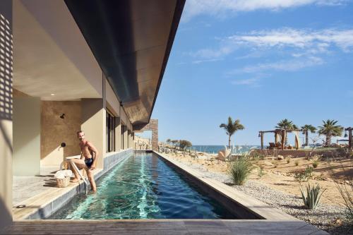 un homme assis dans une piscine à côté d'une maison dans l'établissement Zadún, a Ritz-Carlton Reserve, à San José del Cabo