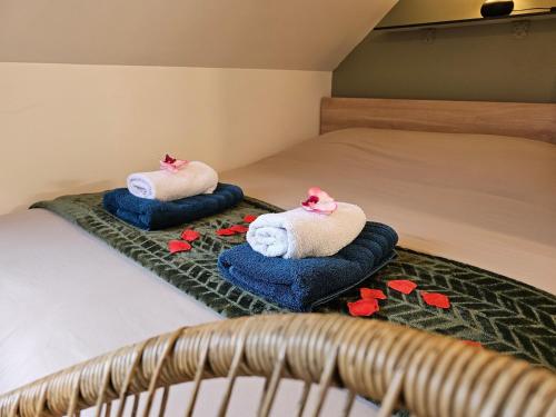 two towels on a bed with red flowers on it at Logement de caractère en haute ville de Quimperlé in Quimperlé