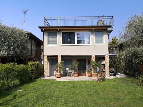 ein großes weißes Haus mit Rasen davor in der Unterkunft Note di lago in Manerba del Garda
