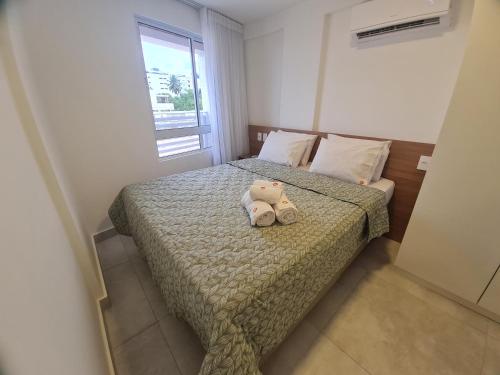 a teddy bear sitting on a bed in a bedroom at PUERTO VENTURA Flat - Cabo Branco by PenareiaTurBr in João Pessoa
