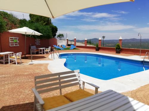 una piscina con banco y sombrilla en Complejo rural Mirador del Condado, en Castellar de Santisteban