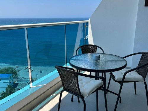 una mesa y sillas en un balcón con vistas al océano en apartamento con vista al mar, en Santa Marta